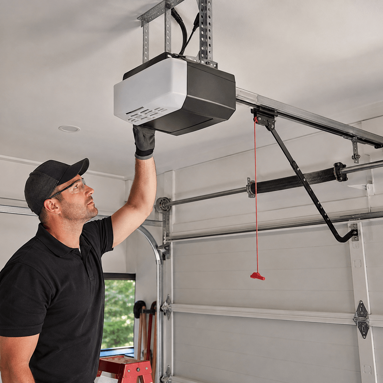 Garage door technician inspecting and adjusting a ceiling-mounted garage door opener